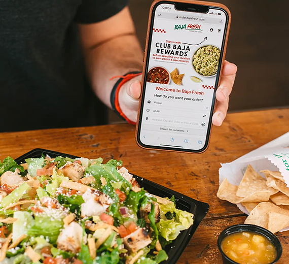 A person holding a phone showing a Club Baja Rewards screen